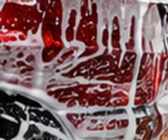 Red vehicle covered in foam during a wash